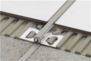 Schluter-DILEX-AKWS features trapezoid-perforated anchoring legs, made of aluminum, which are secured in the mortar bond coat and provide edge protection for adjacent tiles. The profile separates individual fields in the tile covering and accommodates movement via the 1/4&quot; (6 mm)-wide, soft PVC movement zone, which also forms the visible surface. The soft PVC movement zone is connected to the anchoring legs with rigid PVC grip bars and is not replaceable. DILEX-AKWS is suitable for both residential use and medium-duty commercial applications, such as areas subject to moderate mechanical stresses, including light vehicular traffic. In addition, DILEX-AKWS prevents sound bridges, making it ideal for use in sound-rated floors.