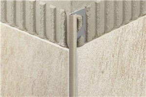 Schluter-RONDEC is a finishing and edge protection profile for the outside corners of tiled surfaces. It features a trapezoid-perforated anchoring leg that is secured in the mortar bond coat beneath the tile and a reveal that forms a symmetrically rounded outer corner with 1/4&quot; (6 mm) radius along the surface edge. The profile is available in stainless steel, solid brass, chrome-plated solid brass, anodized aluminum, color-coated aluminum, and PVC. RONDEC&#39;s wide range of materials, colors, and surface finishes allows for color coordination with tile and grout and the creation of interesting accents in decorative designs. In addition to its decorative effect, the profile protects tile edges against damage caused by mechanical stresses. RONDEC, in stainless steel, is particularly resistant to wear when used as edge protection. It may also be used as a stair nosing or transition profile. RONDEC is suitable for transitions, corners, or dado coverings with other covering materials; for example, carpet, parquetry, natural stone tiles, or cold-cured resin coatings. The integrated joint spacer forms a defined joint cavity with the tile.